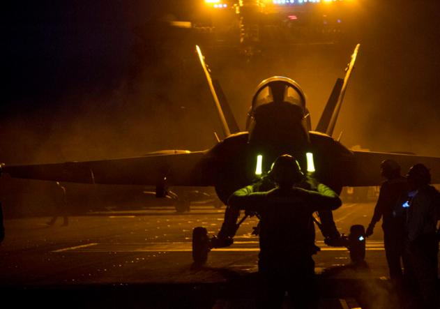 Установка истребителя F/A-18C Hornet в башмак катапульты во время ночных полетов на атомном авианосце USS George H.W. Bush (CVN 77), фото сделано 8 июня 2018 года в Атлантическом океане в период планового учебного выхода корабля с целью поддержания боевой готовности