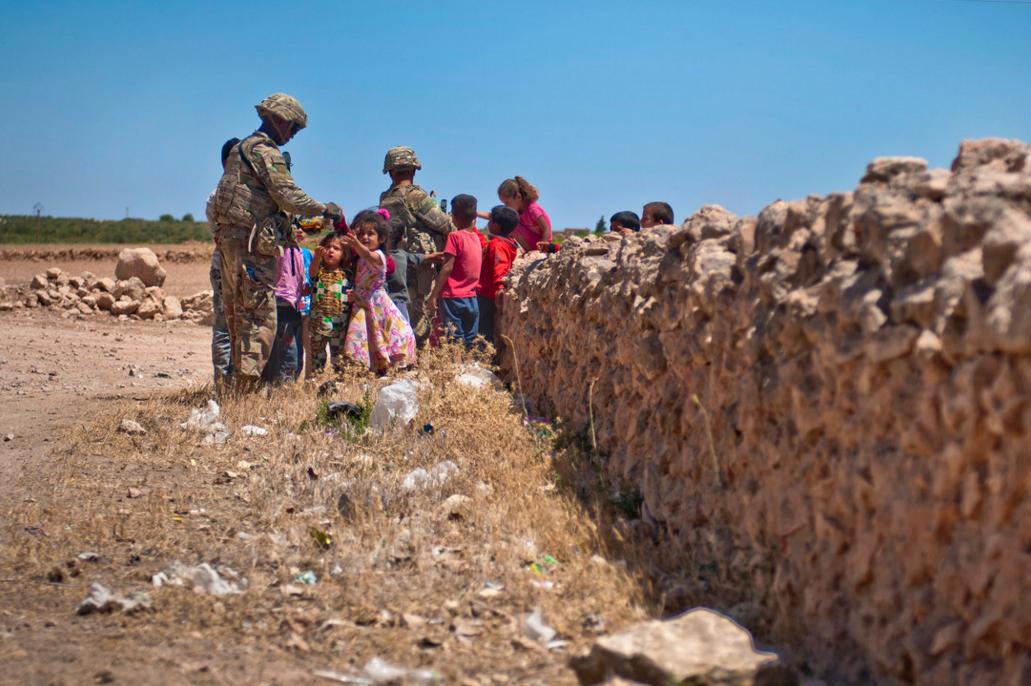 Американские солдаты в Сирии угощают детей конфетами во время независимого патрулирования разграничительной (с Турцией – ред.) линии в районе города Manbij, Сирия, фото сделано 16 июля 2018 года